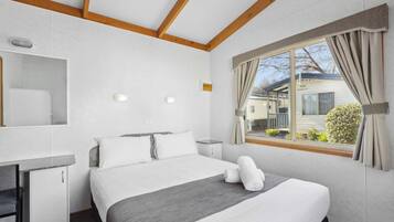 A bedroom with a bed, bedside table, and a window with curtains.