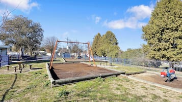 Un parque infantil con columpios, un tobogán y mesas de picnic.