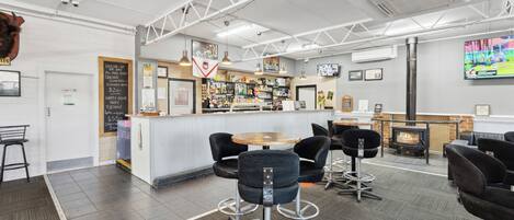 A modern bar area with a counter, stools, and a television screen.