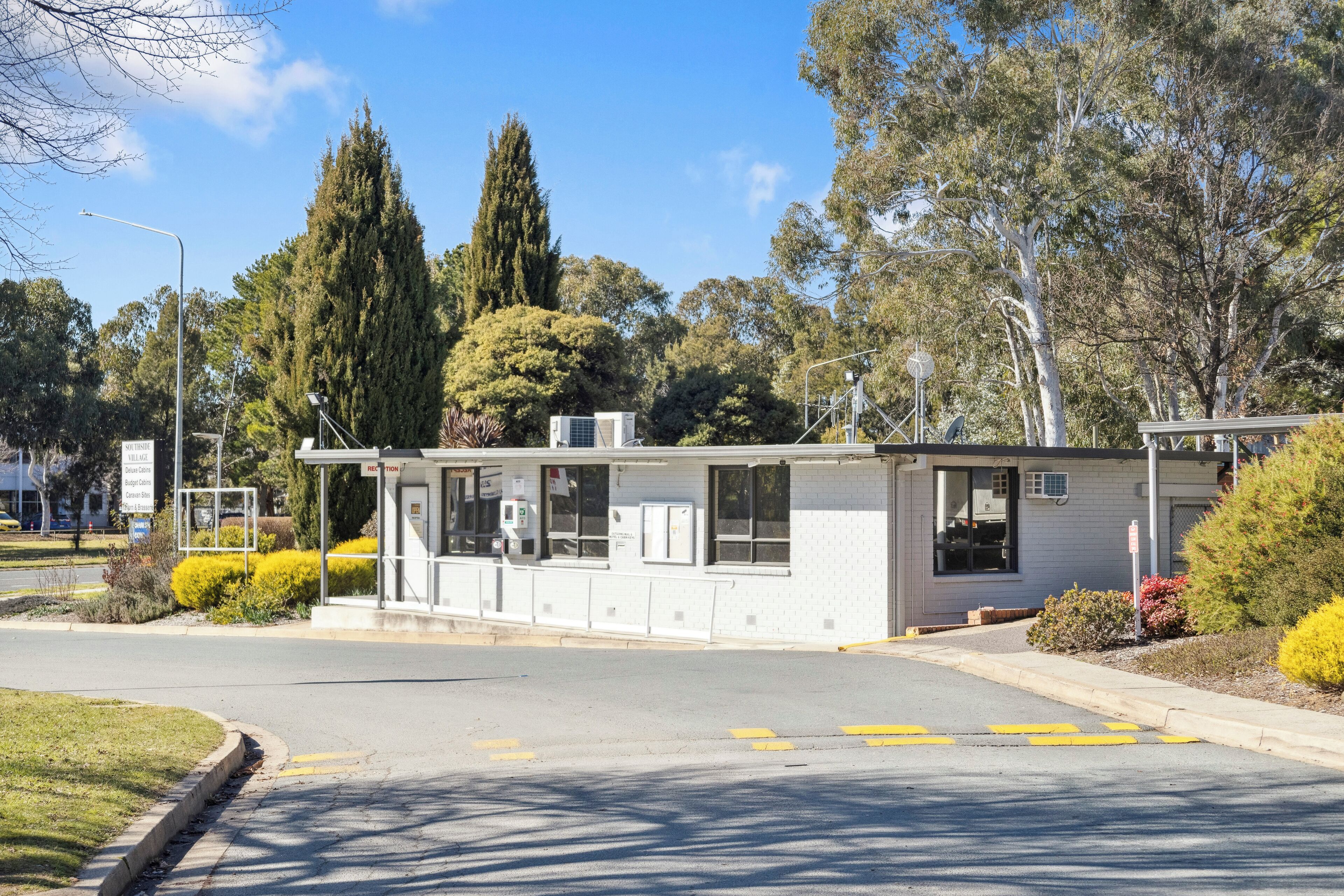A small, single-story building with a flat roof, large windows, and a covered entrance area.