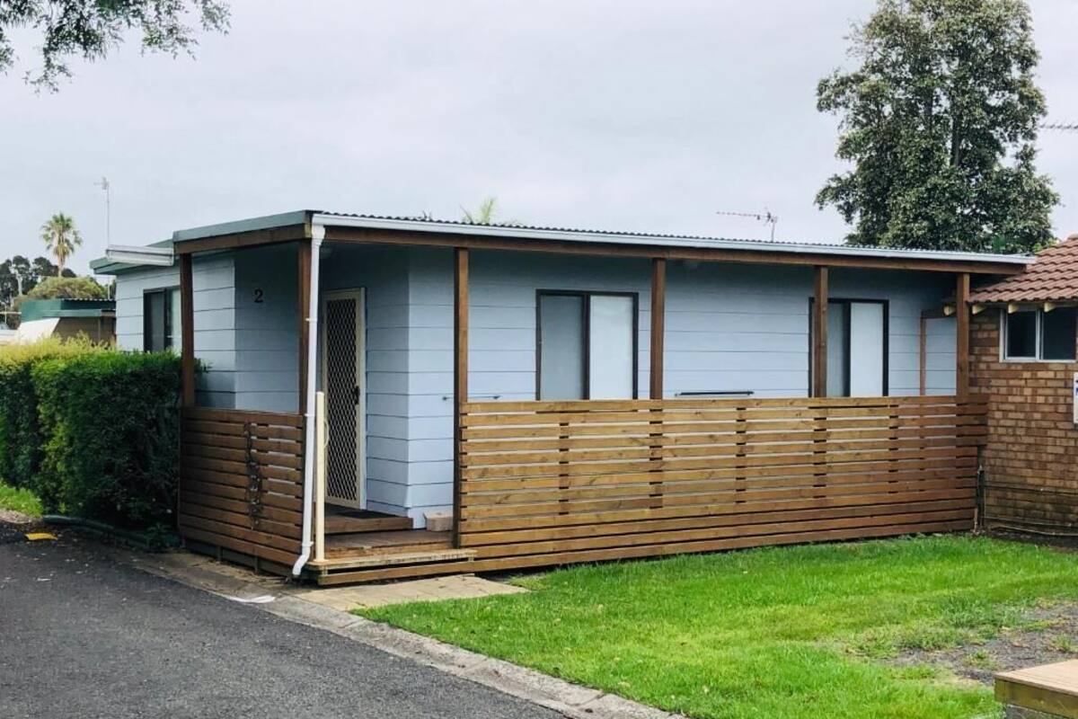 A single-story building with a flat roof, a wooden fence, and a small porch.