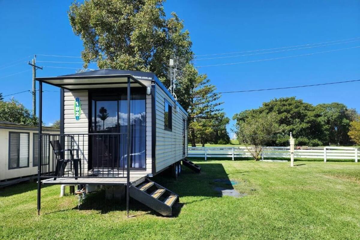A small, single-story mobile home with a porch and a staircase leading to the entrance.