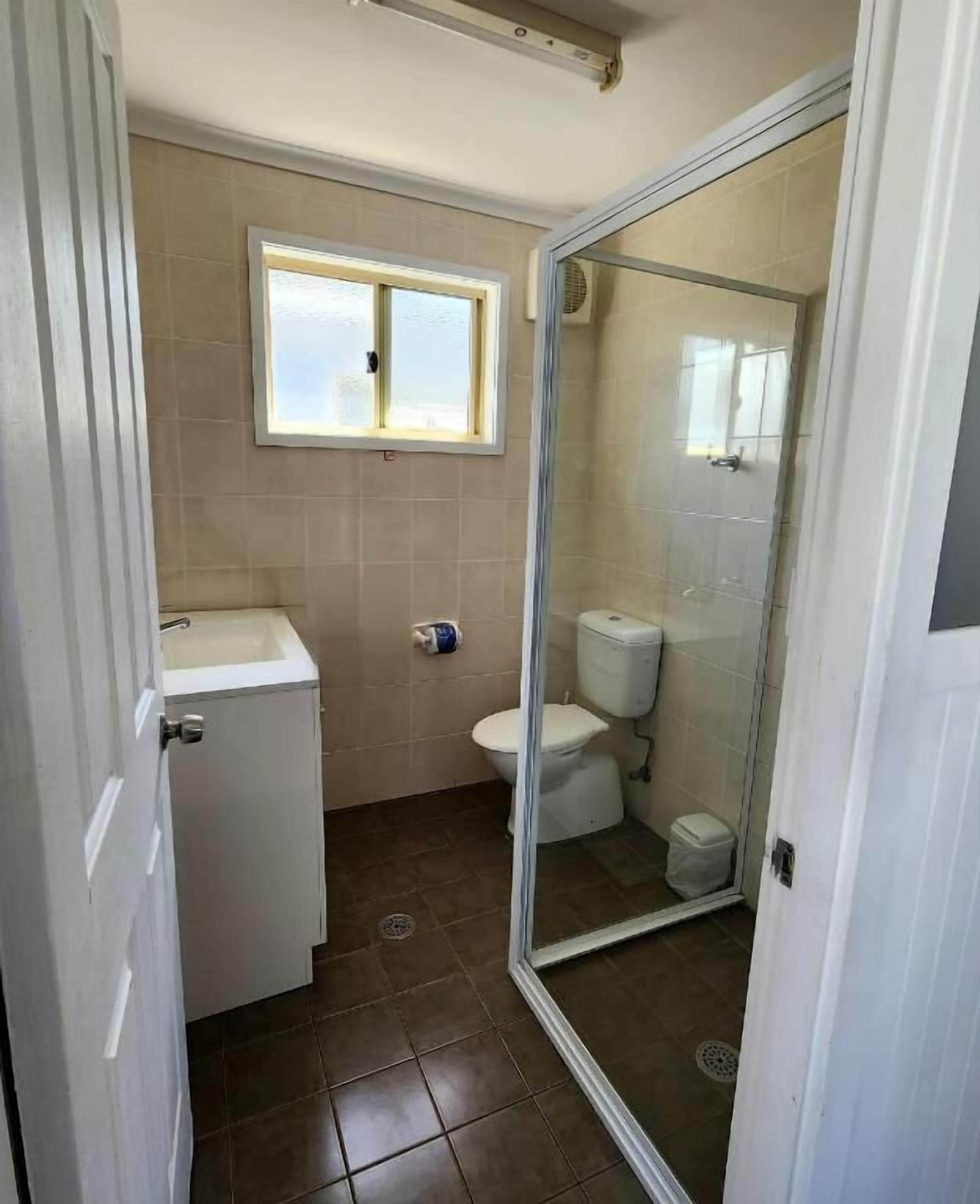 A small bathroom with a toilet, sink, and a window.