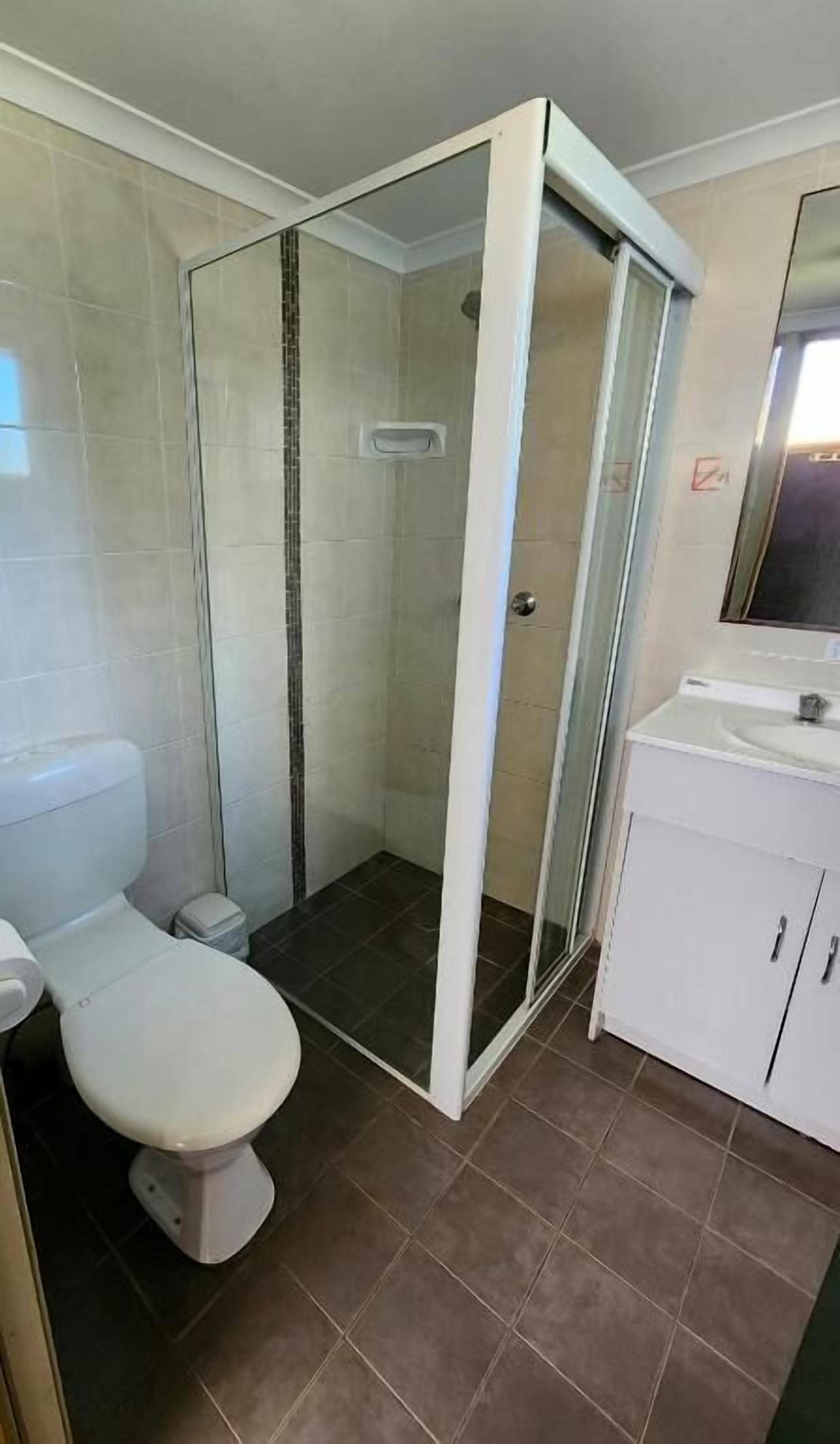 Un bagno con doccia vetrata, un water e un lavandino.