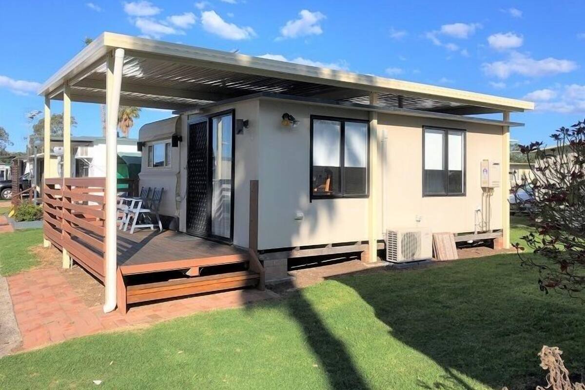 A single-story mobile home with a covered porch, a sliding glass door, and a small attached garage.