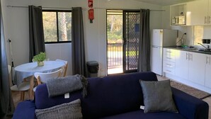 A compact living space with a sofa, dining table, and kitchenette. - Shellharbour Holiday Village (Barrack Point)