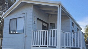 A small, single-story mobile home with a balcony and a porch. - Shellharbour Holiday Village (Barrack Point)