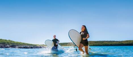 Dos personas corriendo al agua con tablas de surf.