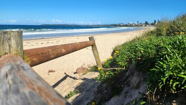A beach with a wooden fence, sandy shore, and a clear blue sky. - Shellharbour Holiday Village (Barrack Point)