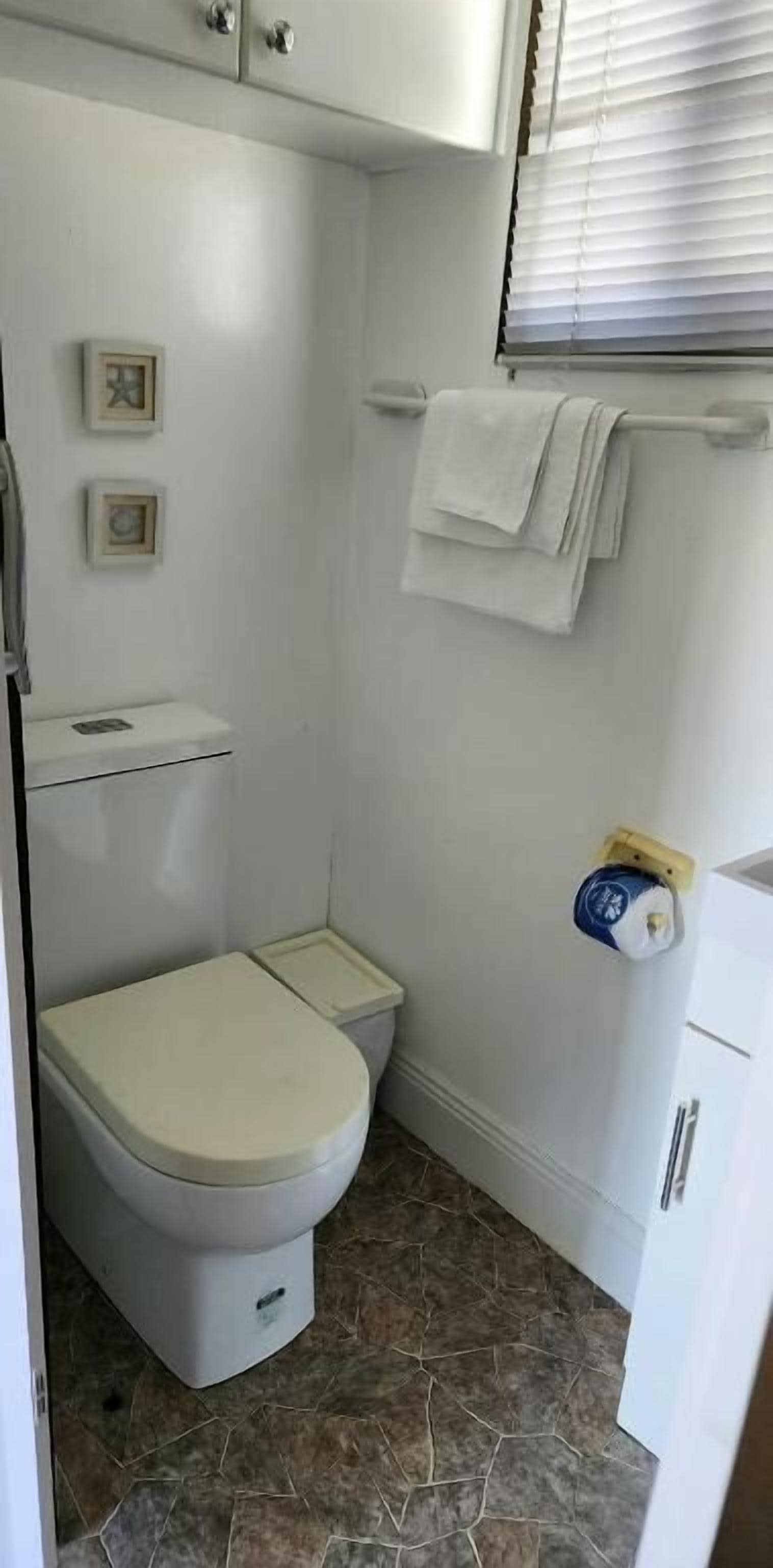 A small, clean bathroom with a toilet, a towel rack with towels, and a toilet paper holder.