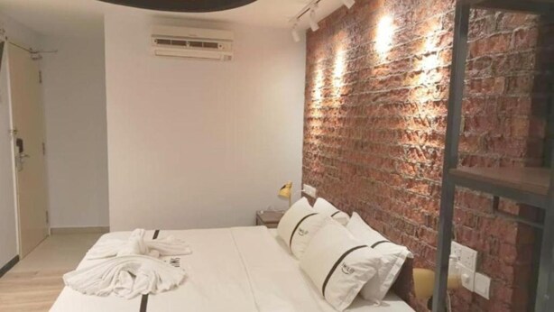 A hotel room with a bed, a brick wall, and a ceiling light fixture. - Smile Hotel Cheras Taman Segar (Kuala Lumpur)