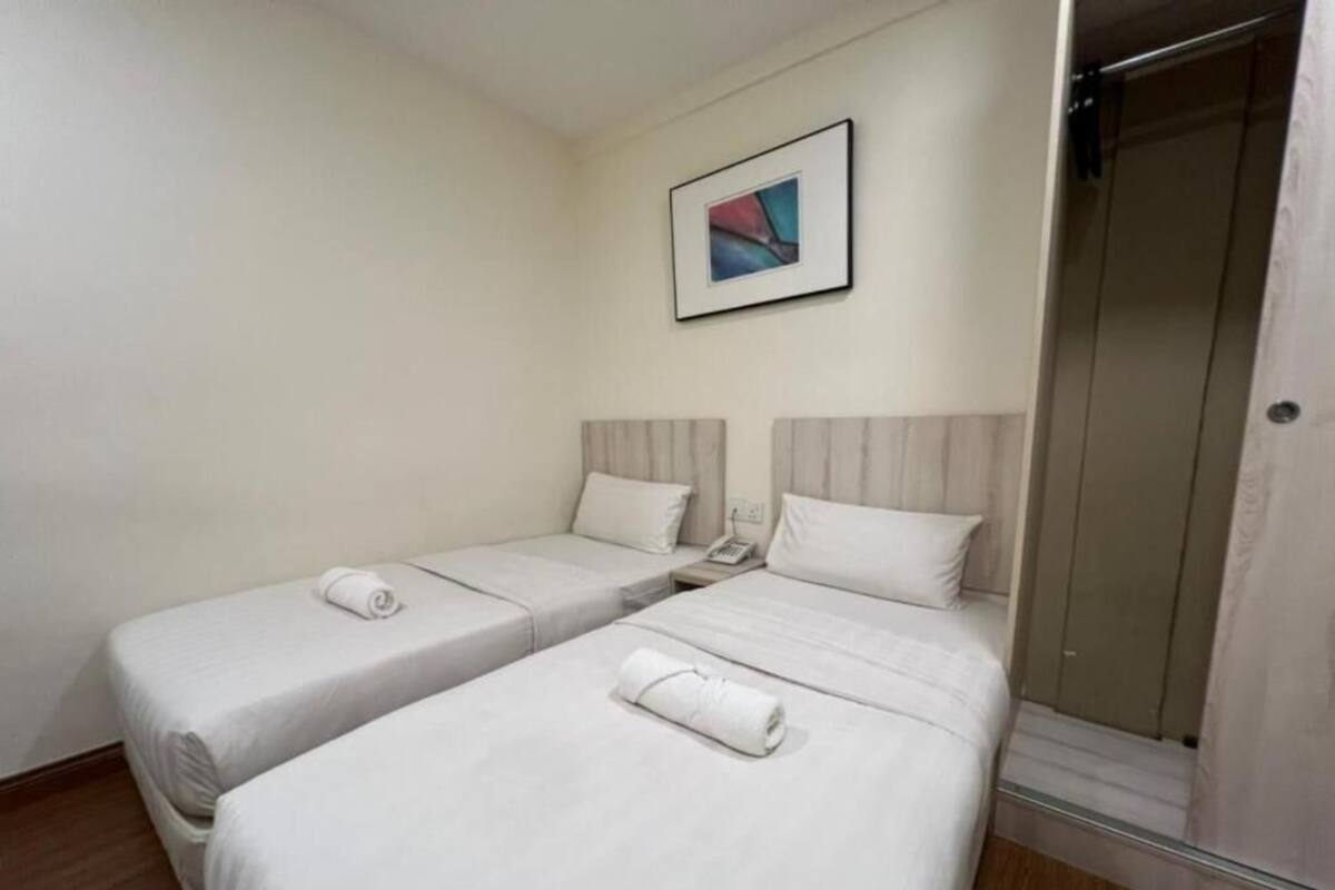 Een hotelkamer met twee bedden, een douche en een ingelijste foto aan de muur.
