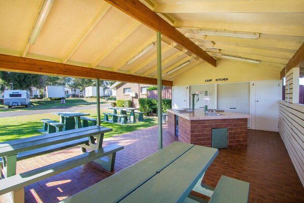 A covered outdoor area with picnic tables, a kitchen, and a view of the surrounding area. - Toowoomba Caravan Park (Kearneys Spring)