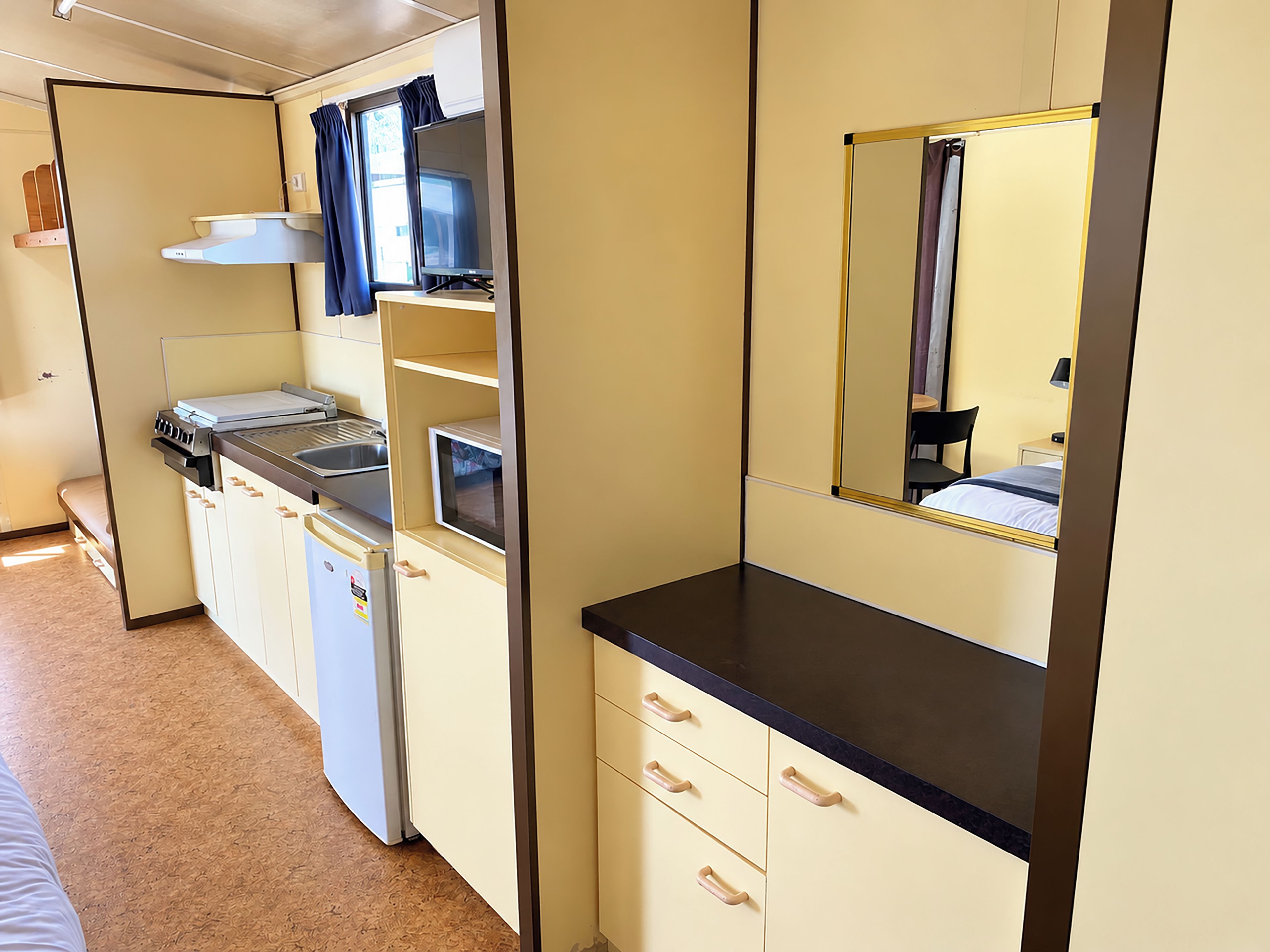 A compact kitchenette with a microwave, stove, and sink.