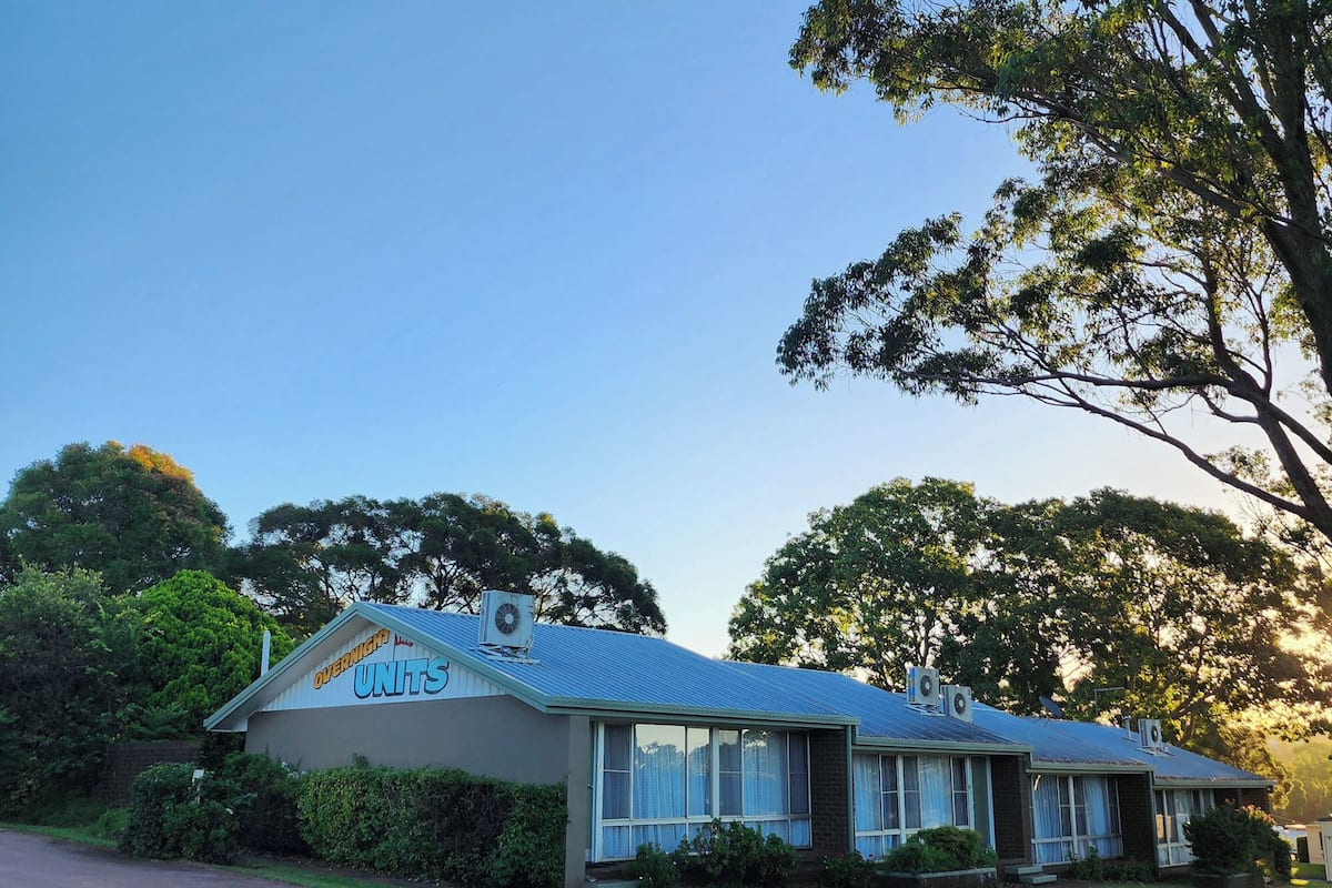 A two-story building with a blue roof, large windows, and a sign that reads "OVERNIGHT UNITS."