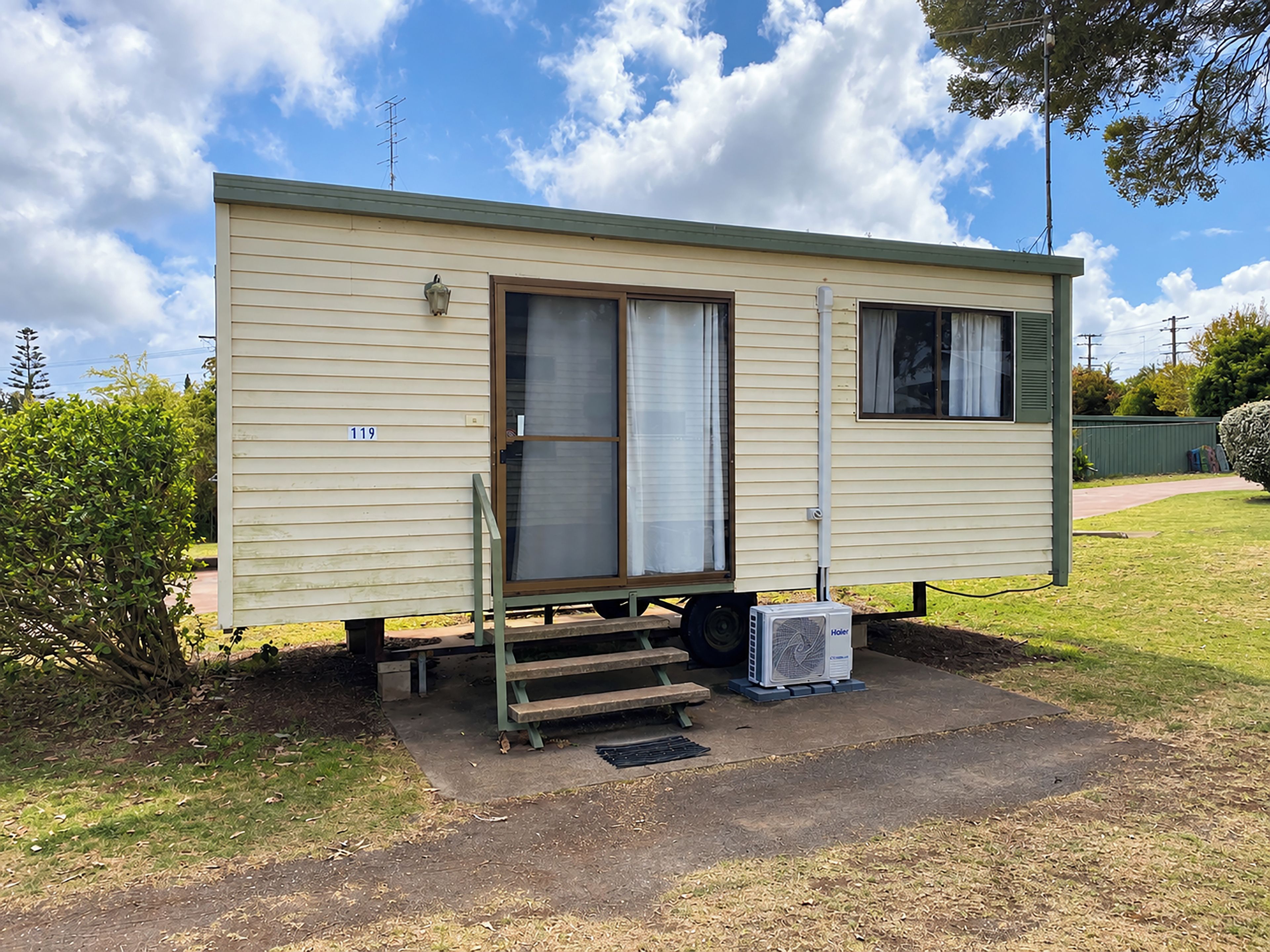 A single-story mobile home with a front door, a small window, and a number '119' on the side.