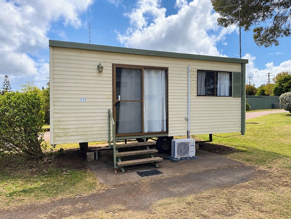 A single-story mobile home with a front door, a small window, and a number '119' on the side.