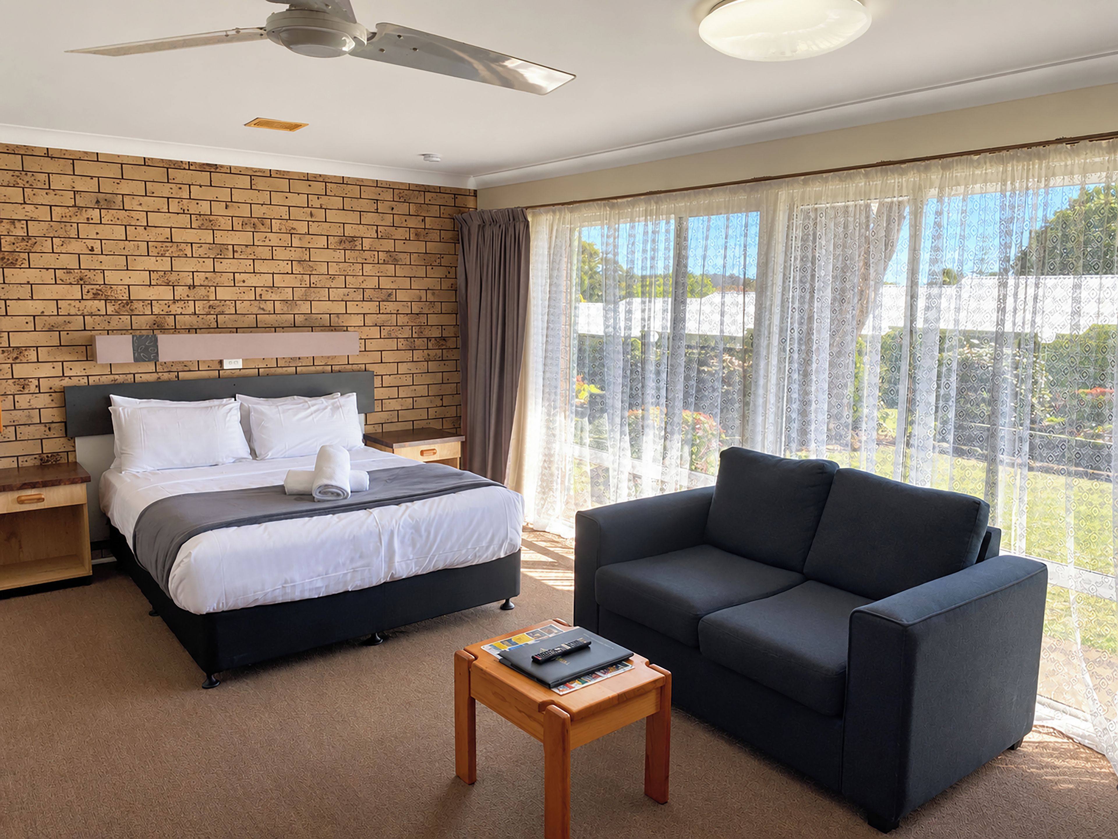 Une chambre d’hôtel avec un lit, un canapé, une petite table et un ventilateur de plafond.