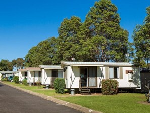A row of mobile homes with a grassy lawn and trees in the background. - Toowoomba Caravan Park (Kearneys Spring)