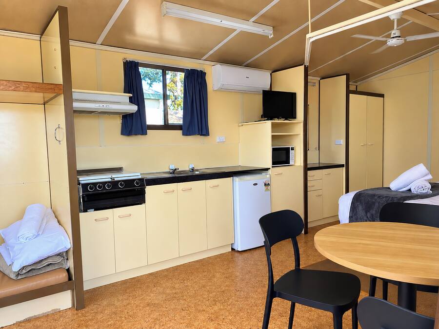 A compact kitchenette with a stove, microwave, and refrigerator. There is a small dining area with a table and chairs.