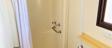A shower with a curtain, a bathtub, a towel rack, and a window.