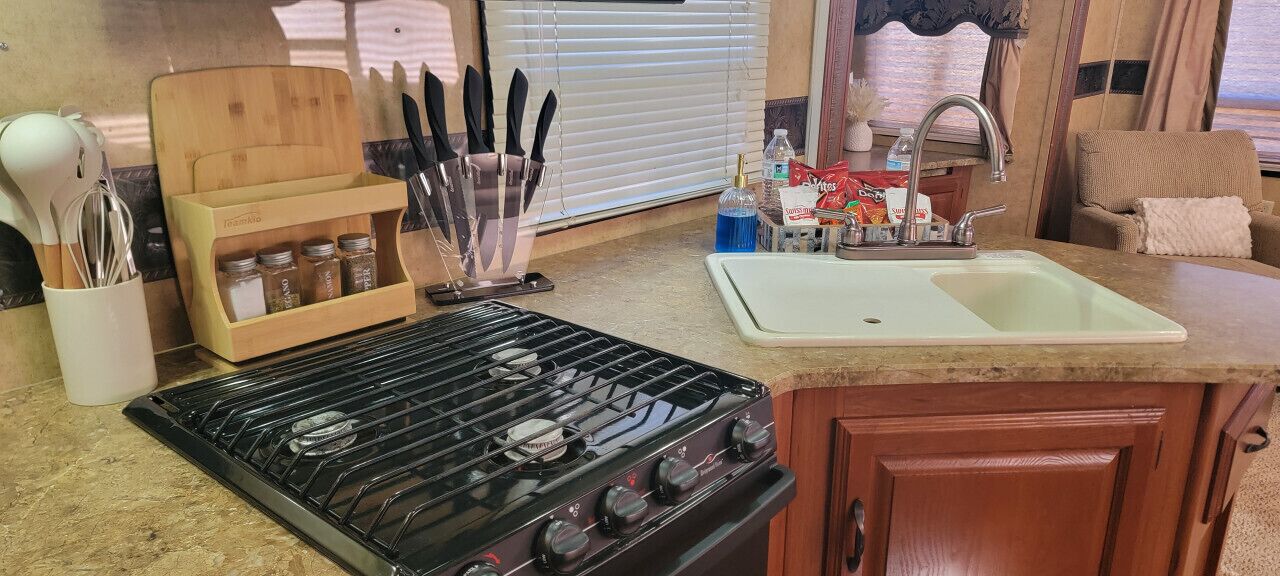 A compact kitchen with a stove, sink, and wooden utensil holder.