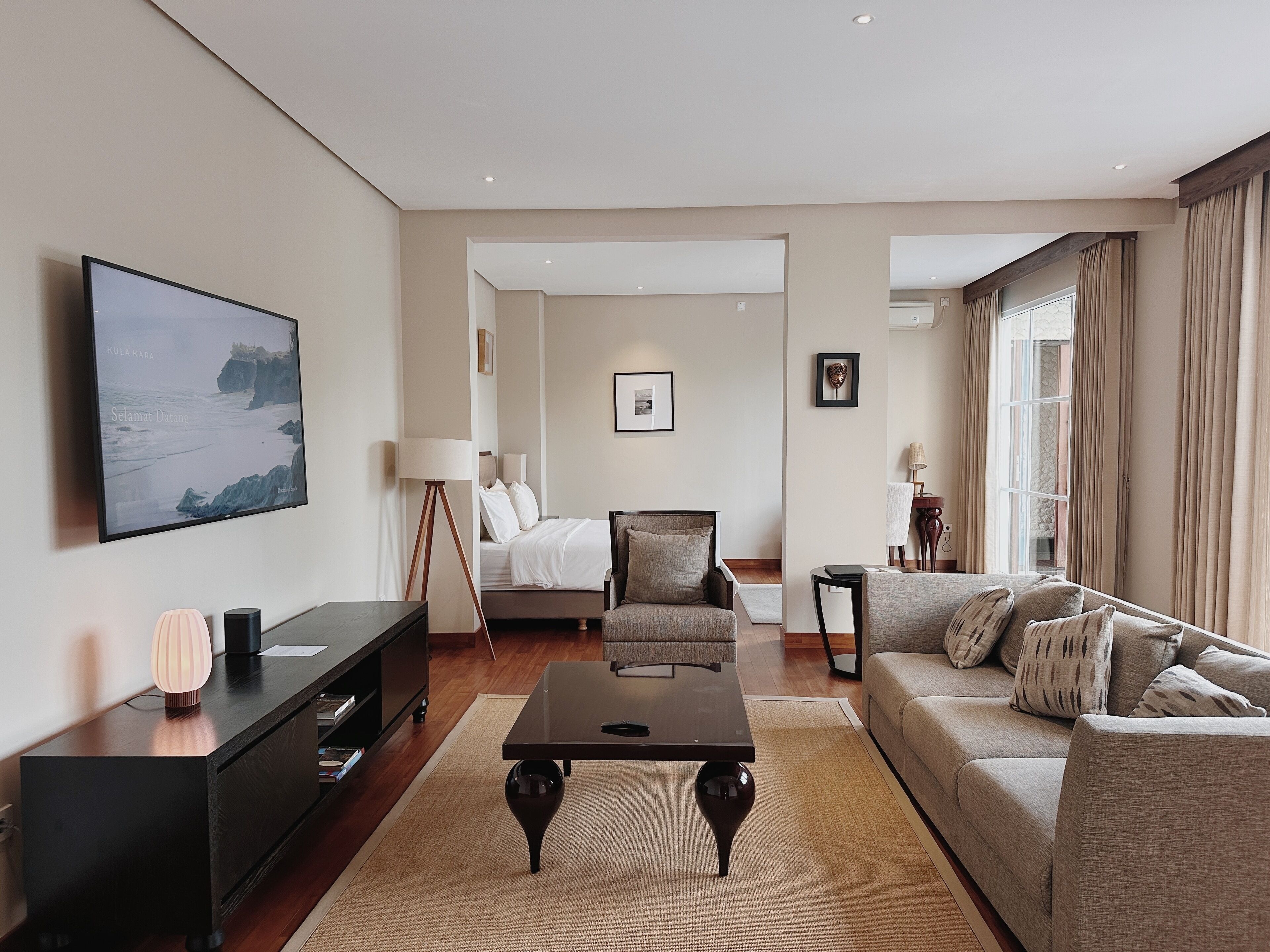 Une chambre d’hôtel moderne équipée d’un grand lit, d’un canapé, d’une table basse, d’une télévision et d’un bureau avec une lampe.