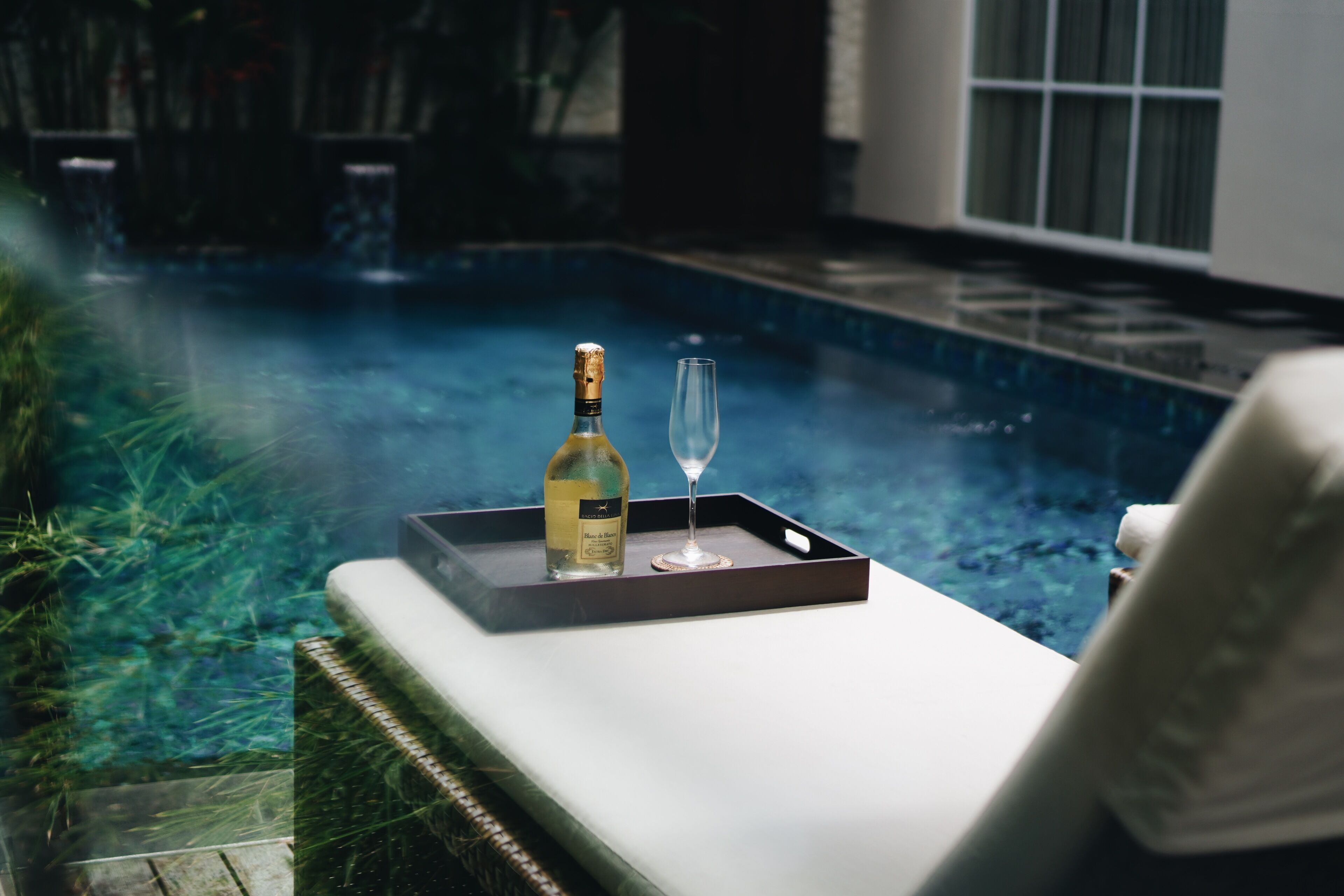 Ein Poolbereich mit einer Champagnerflasche und einem Glas auf einem Tablett.
