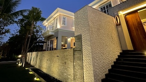 Una casa moderna con fachada de piedra, escalera de madera y una entrada bien iluminada.