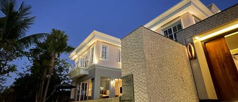 A modern house with a stone facade, a wooden staircase, and a well-lit entrance.