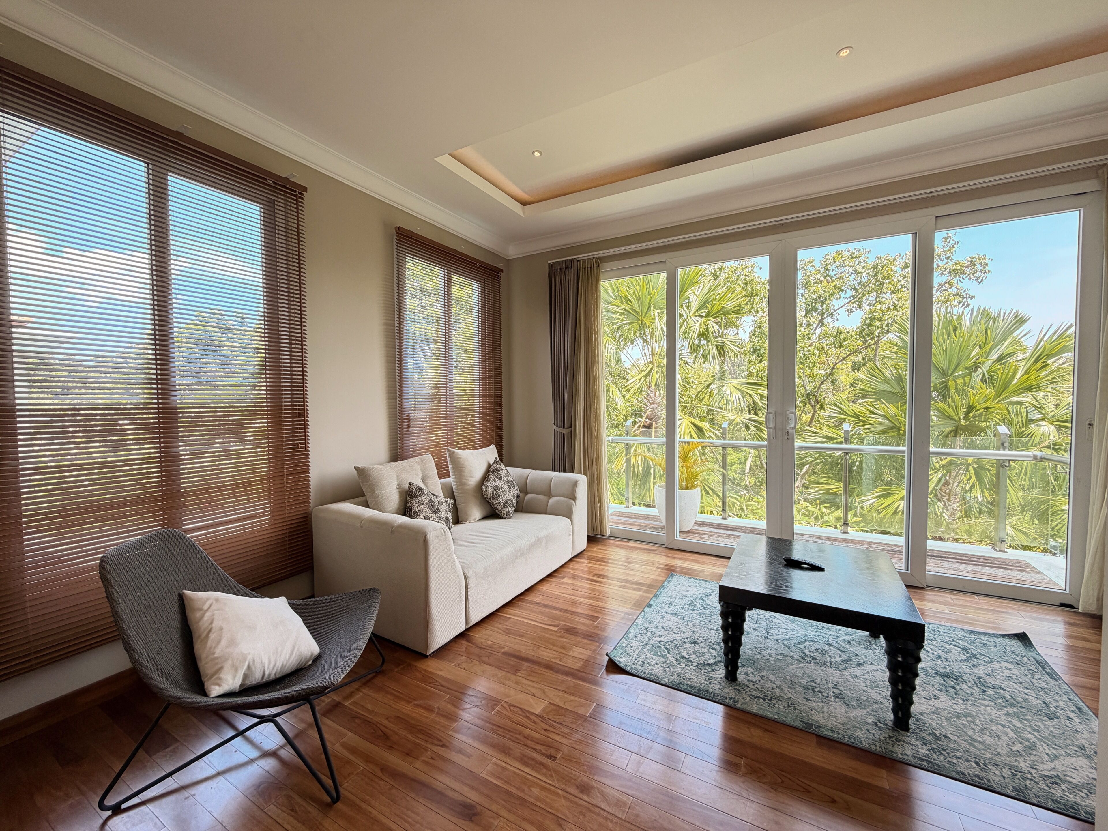 Un salón espacioso con sofá, sillón, mesa de centro y grandes ventanales con vistas a zonas verdes.