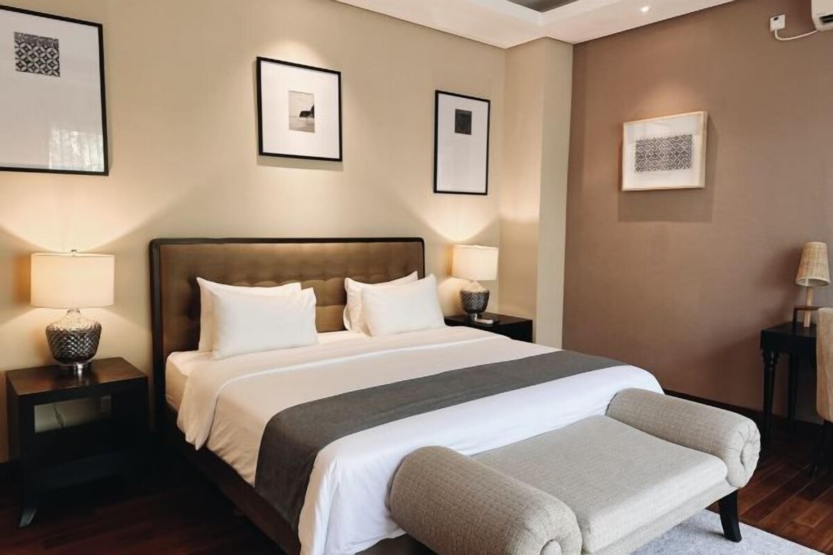 A neatly arranged hotel room with a large bed, two bedside tables with lamps, and framed artwork on the walls.