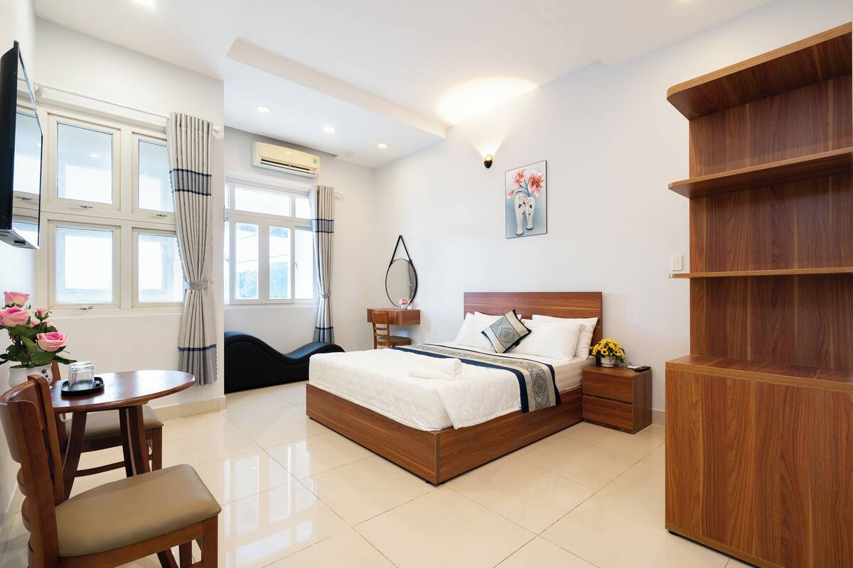 A modern bedroom with a wooden bed, bedside tables, a desk, and a chair.