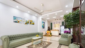 A modern hotel lobby with a green sofa, a coffee table, and a reception desk. - Green Airport Hotel (Ho Chi Minh City)