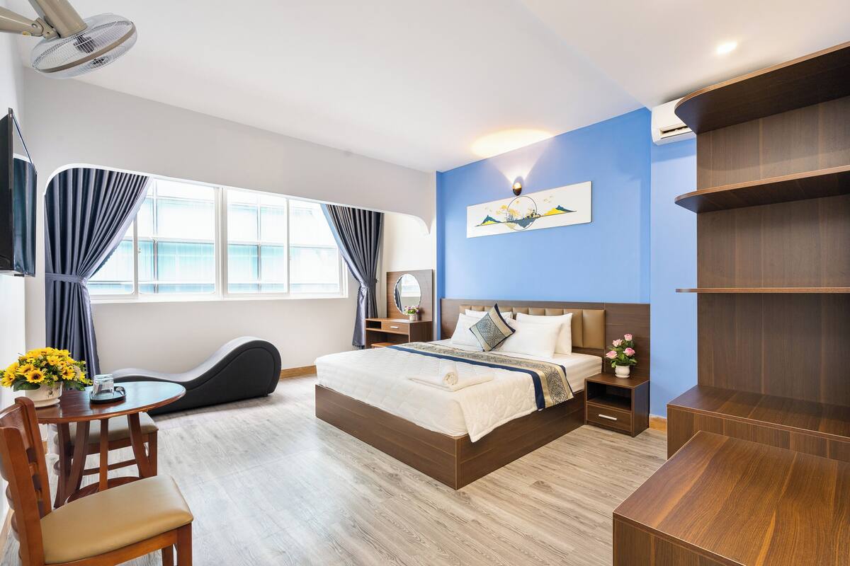 A modern hotel room with a large bed, bedside tables, a desk, and a chair.