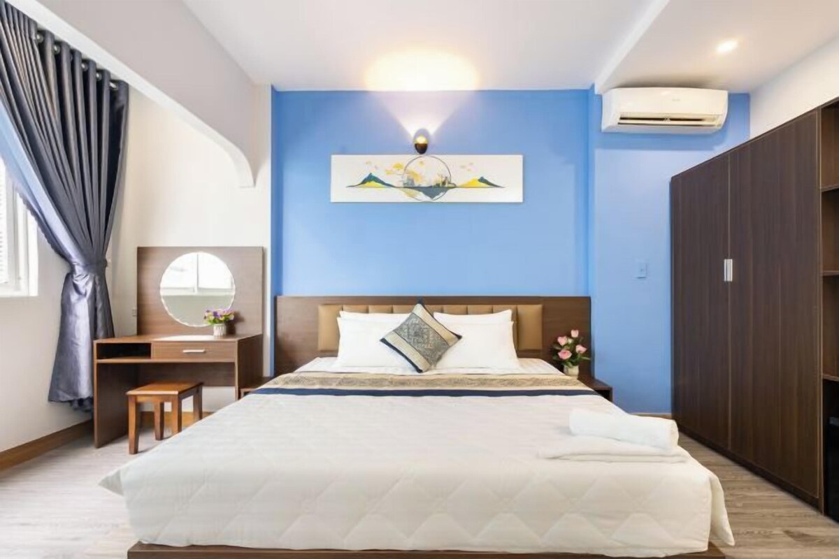 A bedroom with a bed, a desk, a chair, a dresser, and a wall-mounted air conditioner.