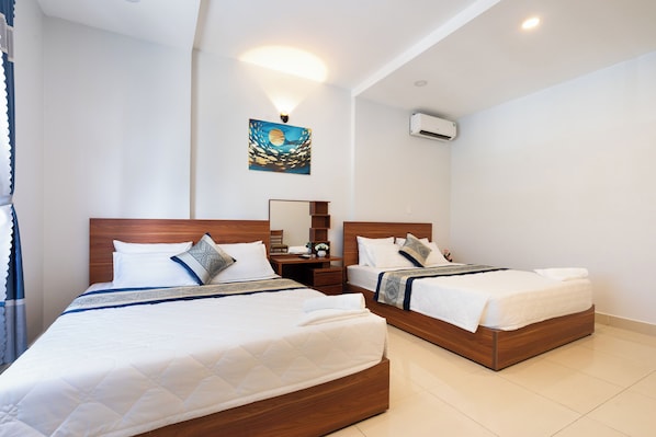 A hotel room with two beds, a nightstand, a desk, and a wall-mounted air conditioner. - Green Airport Hotel (Ho Chi Minh City)