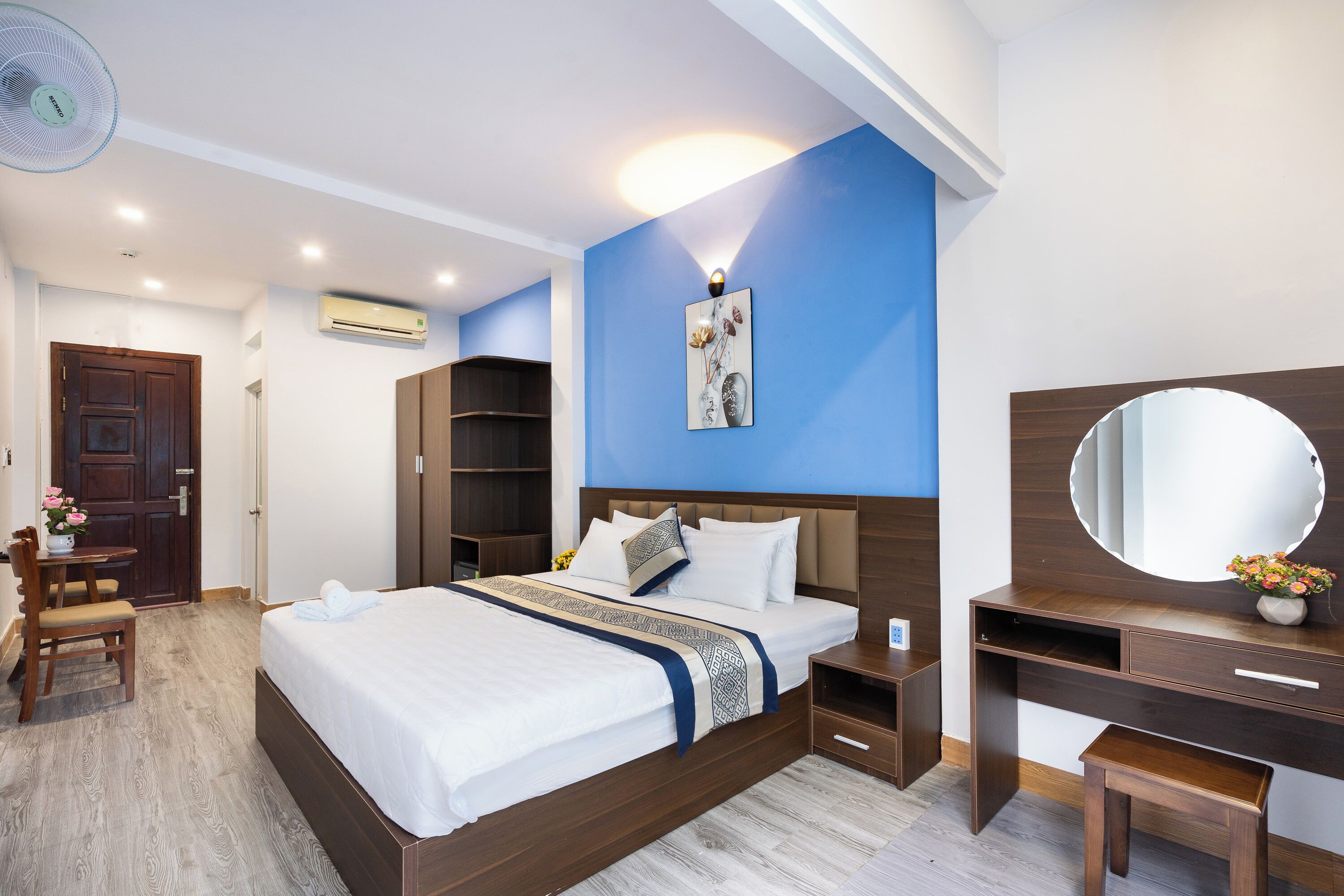 Une chambre d’hôtel comprenant un lit, une table de chevet, une commode et un miroir.