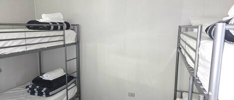 A dormitory room with bunk beds, a patterned floor, and a plain wall.