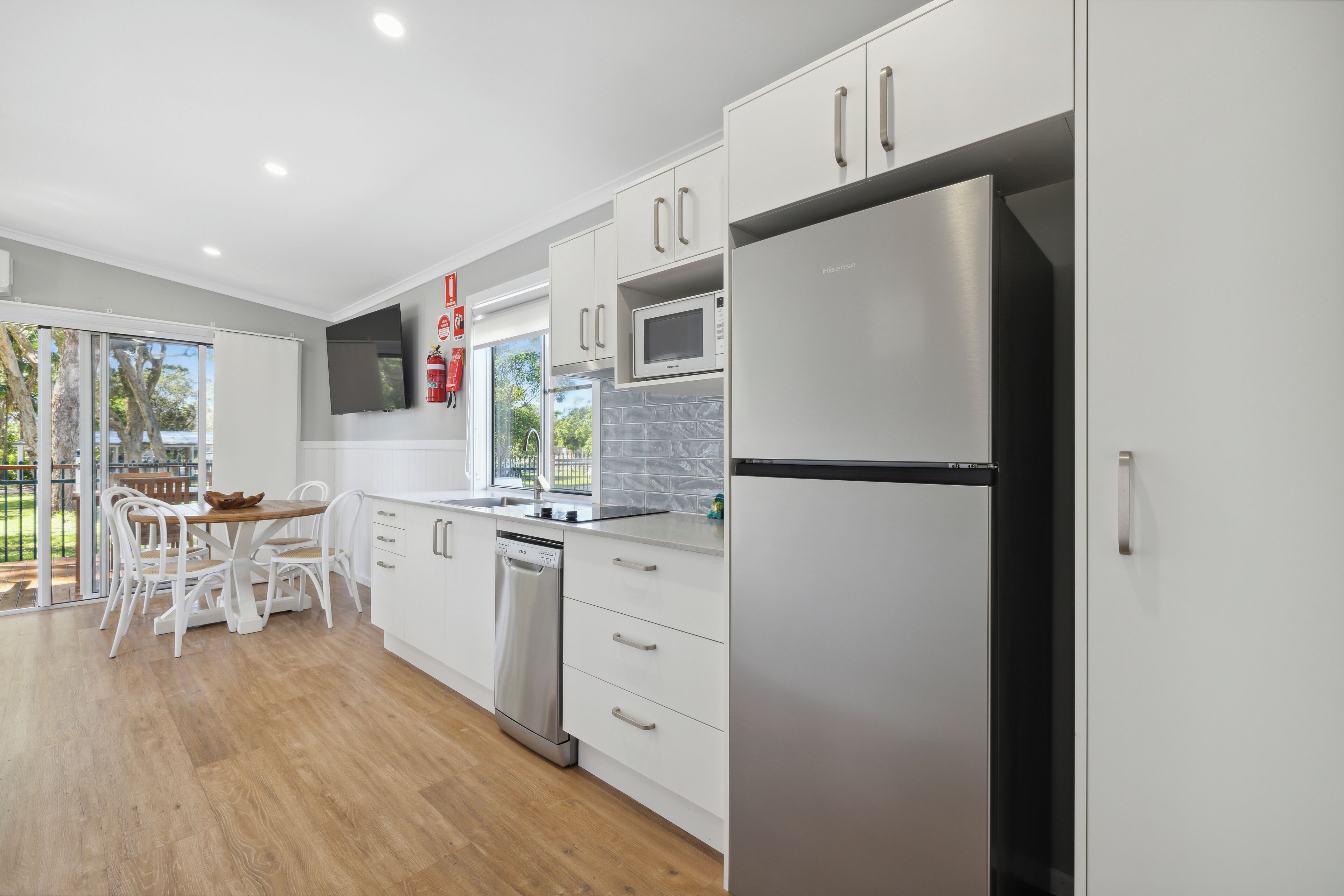 A modern kitchen with white cabinets, stainless steel appliances, and a wooden dining table.