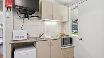 A compact kitchen with a microwave, toaster, and sink.