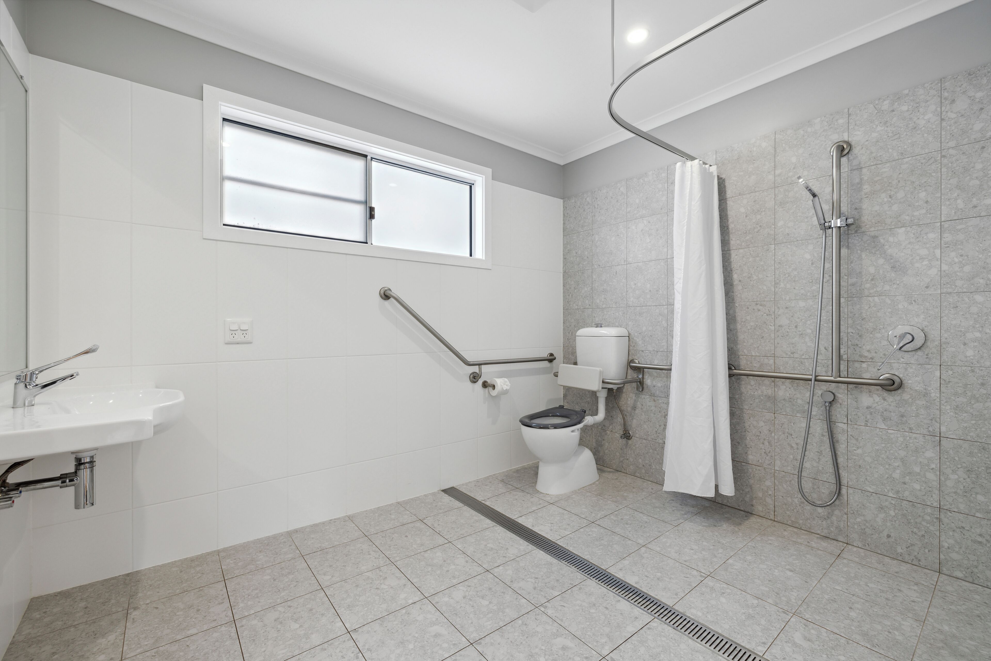 A modern bathroom with a toilet, sink, and shower.