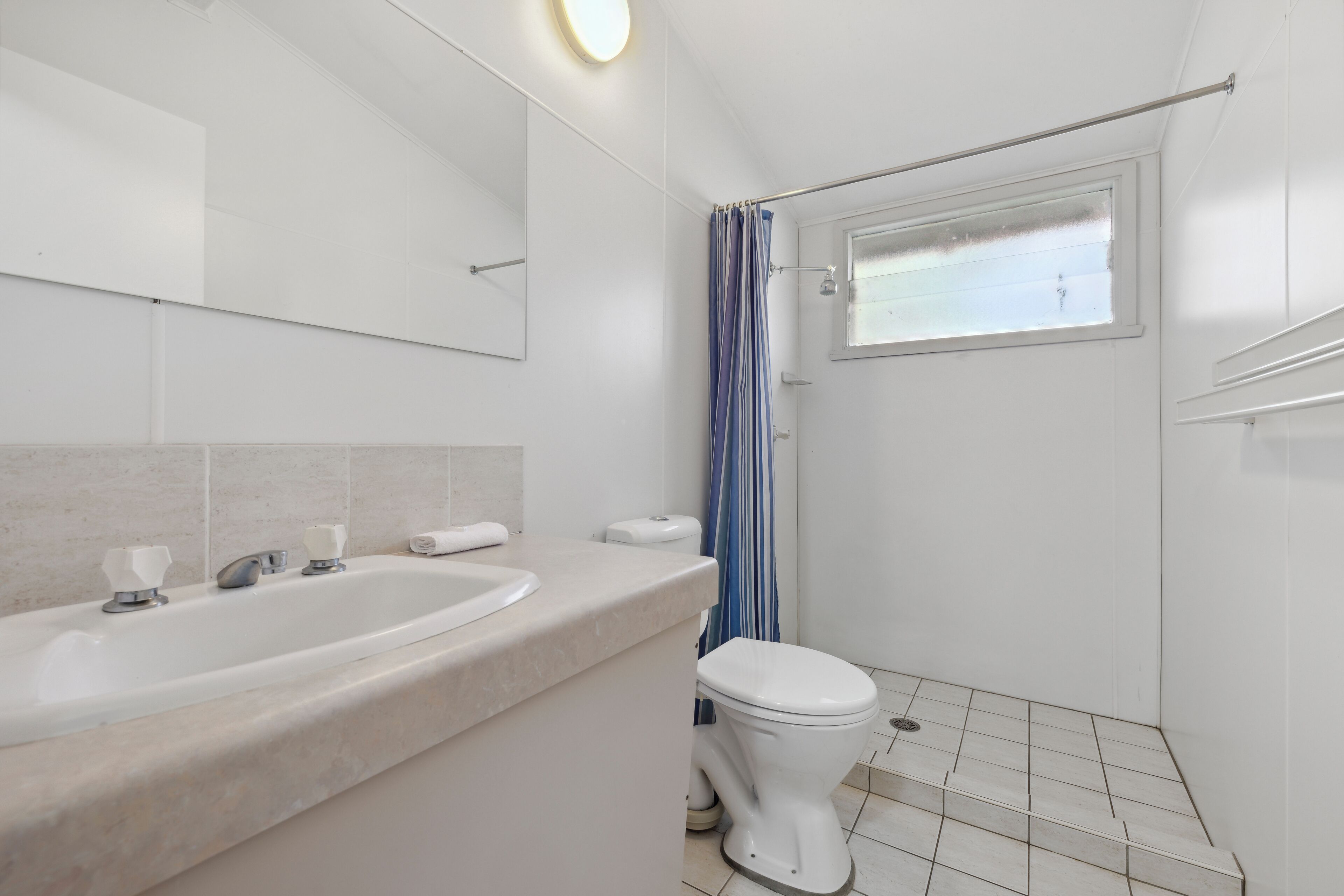 Une salle de bain avec une baignoire, des toilettes et une fenêtre.