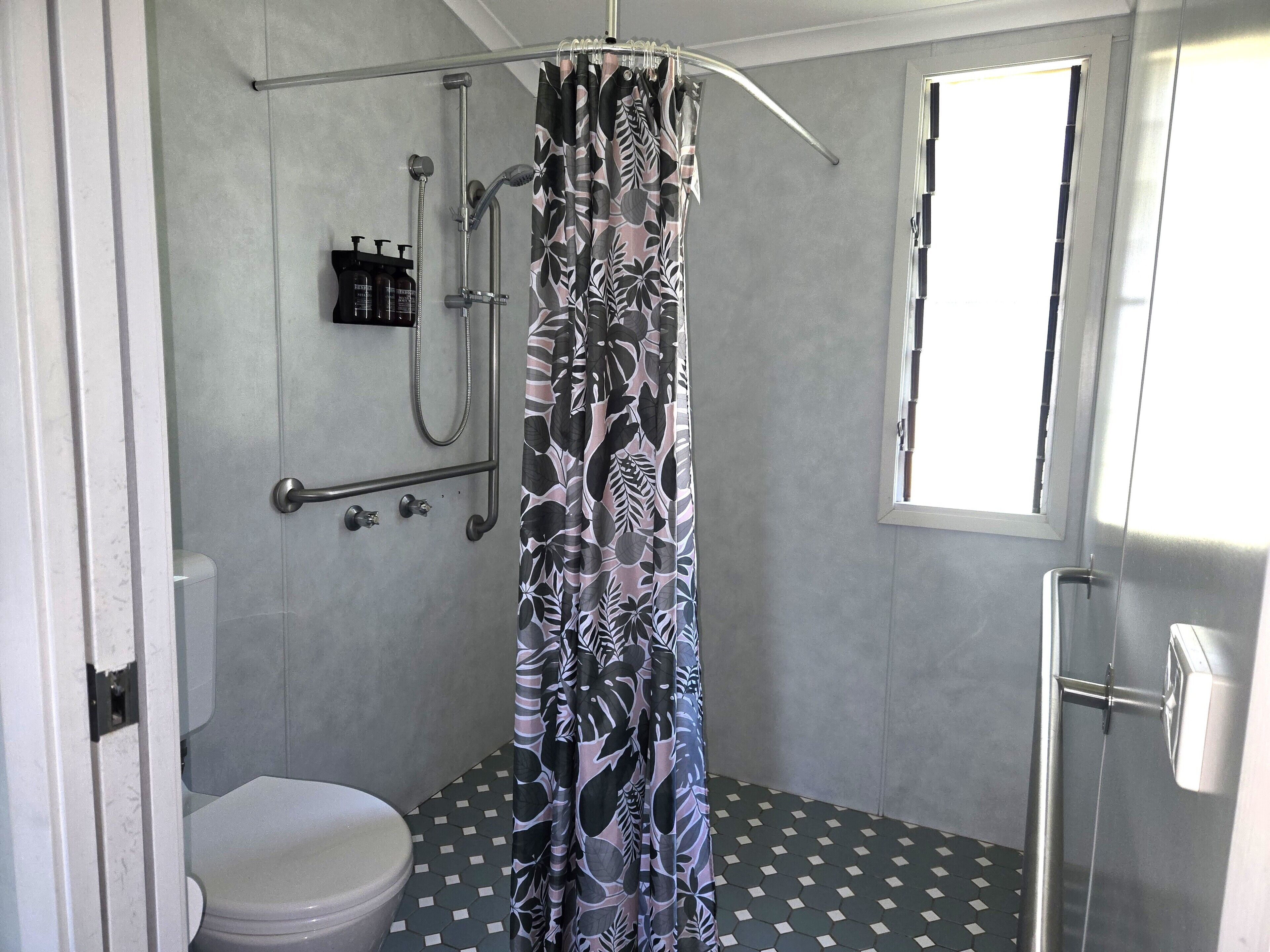 Un baño con ducha, inodoro y ventana.