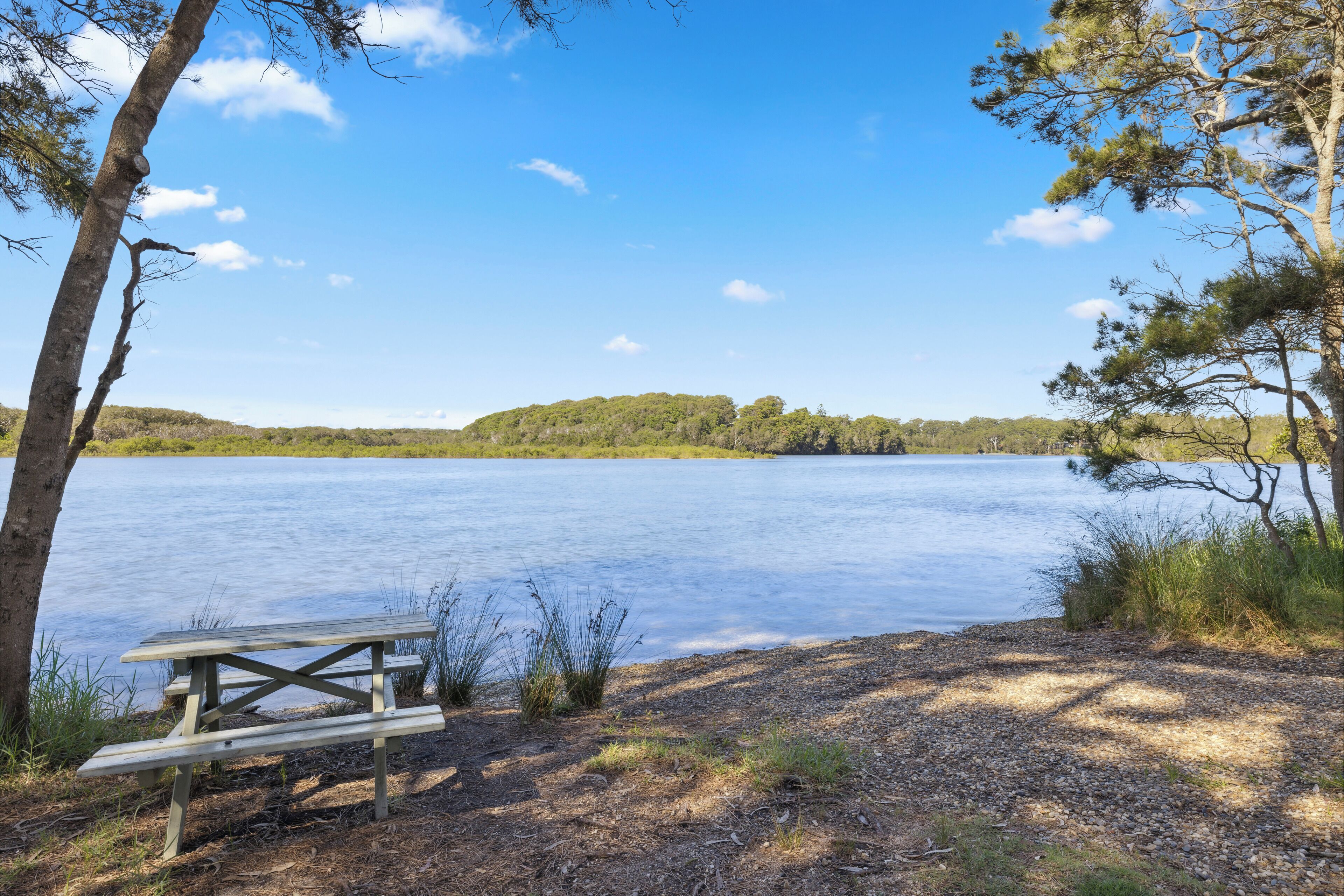 Järvenrantainen piknikpöytä, josta avautuu esteetön näkymä järvelle ja kaukaisiin kukkuloihin.