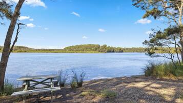 Una mesa de picnic junto al lago, con una vista despejada del lago y colinas lejanas.