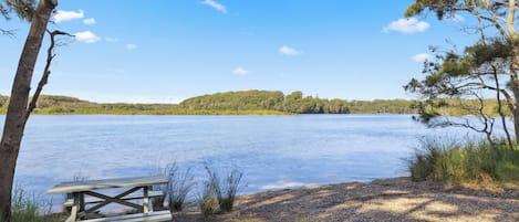 Järvenrantainen piknikpöytä, josta avautuu esteetön näkymä järvelle ja kaukaisiin kukkuloihin.