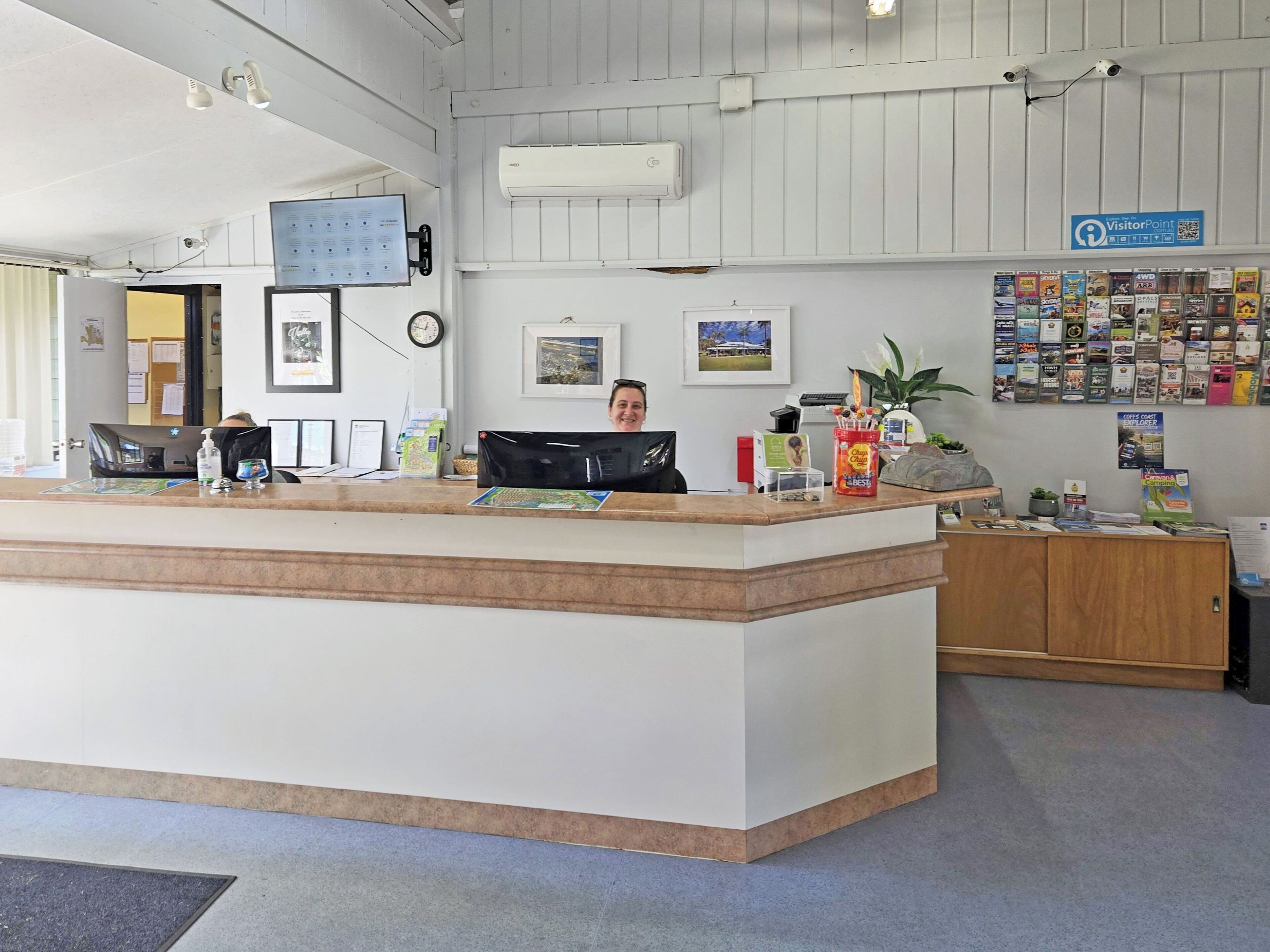 A reception area with a counter, a computer, a clock, framed pictures, and a wall with brochures.