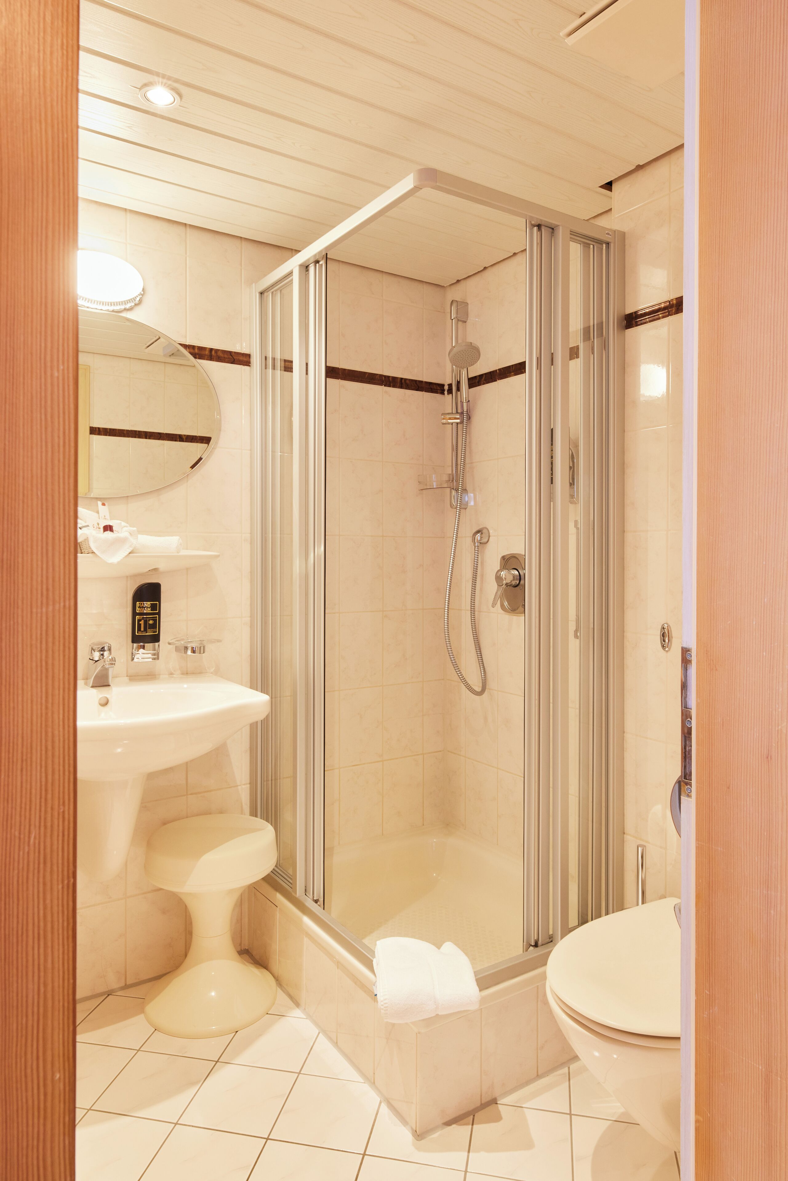Et moderne badeværelse med et glasafskærmet brusebad, en vask og et toilet.