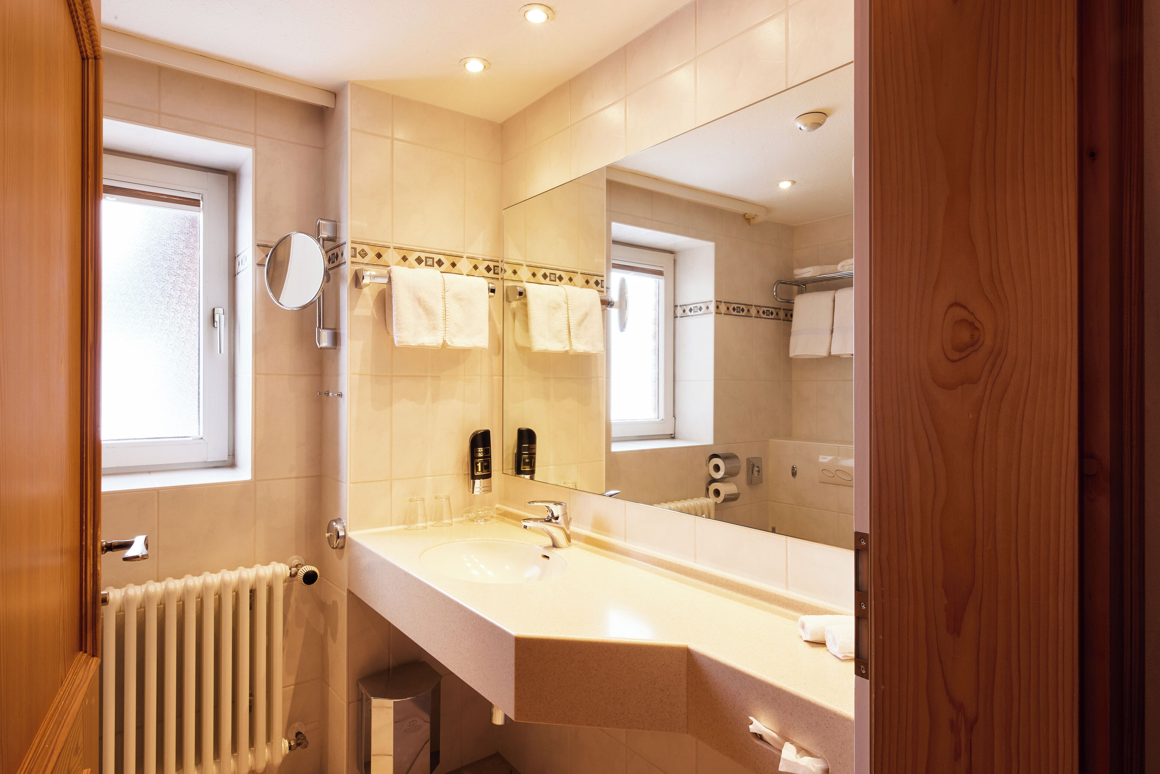 Un baño moderno con un espejo grande, un lavamanos y un perchero para toallas.
